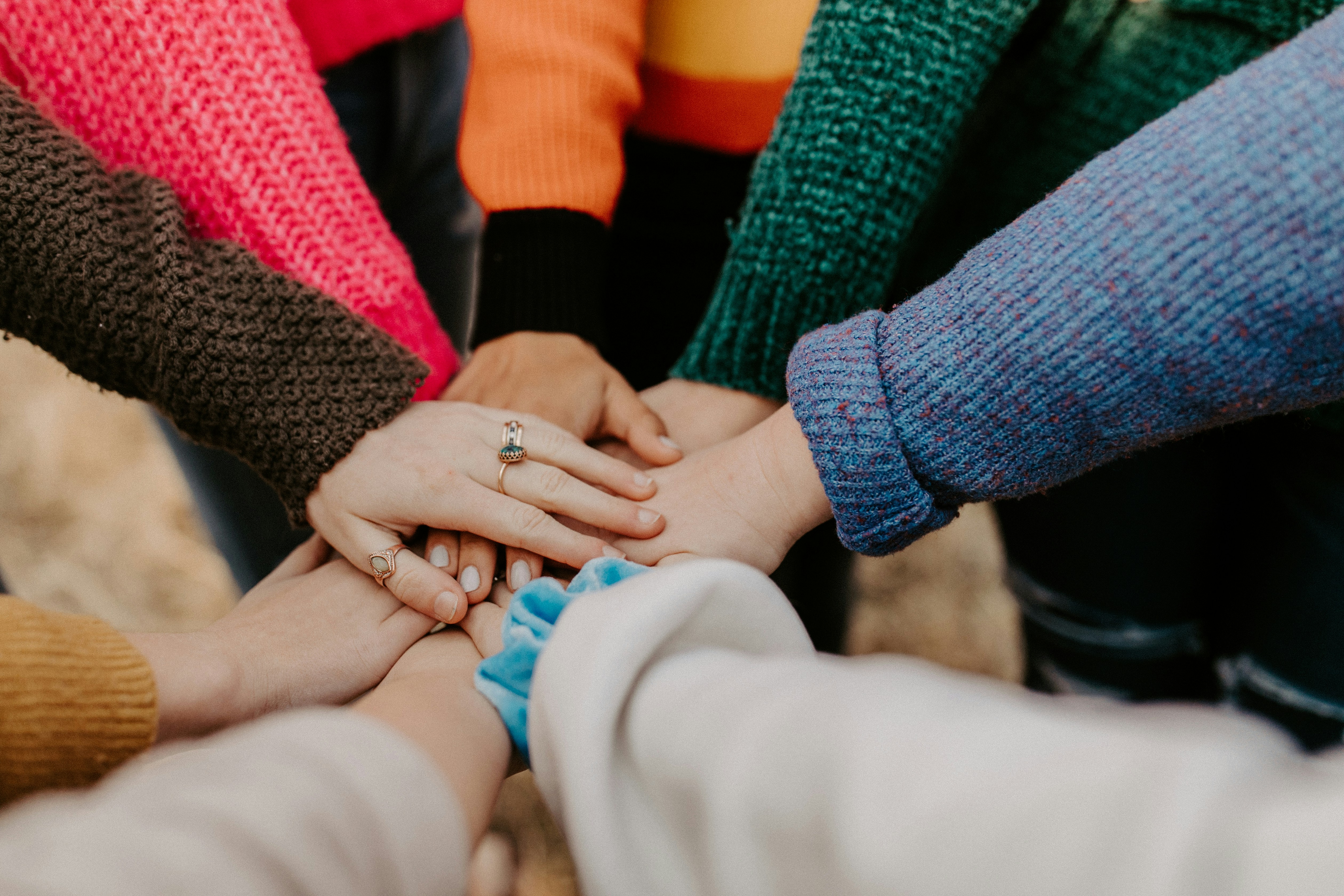 group of people in a circle with their hands on top of each other